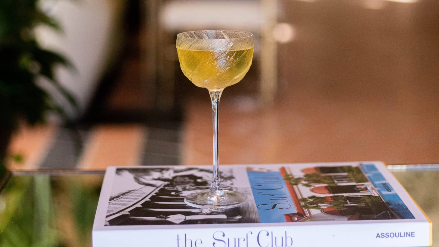 An amber cocktail resting on a large coffee book.
