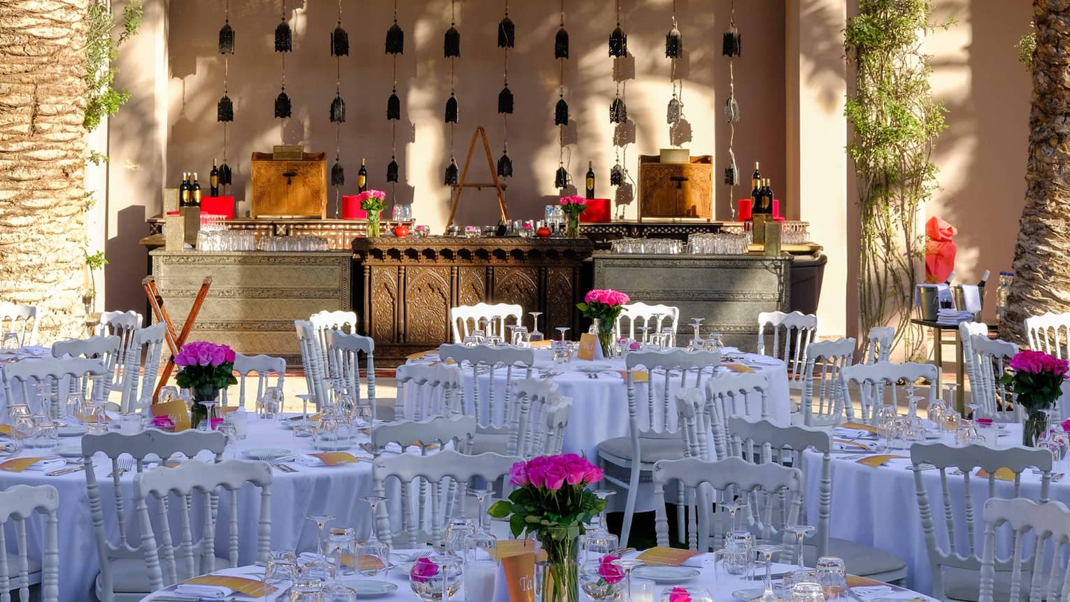 Palm trees over round banquet dining tables with white linens 
