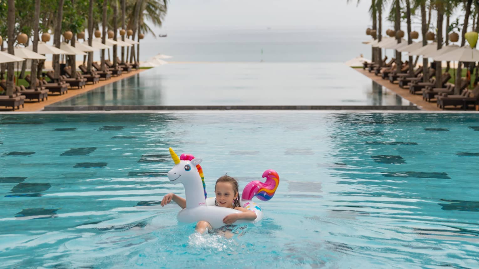 Girl using a unicorn floatie in the infinity pool