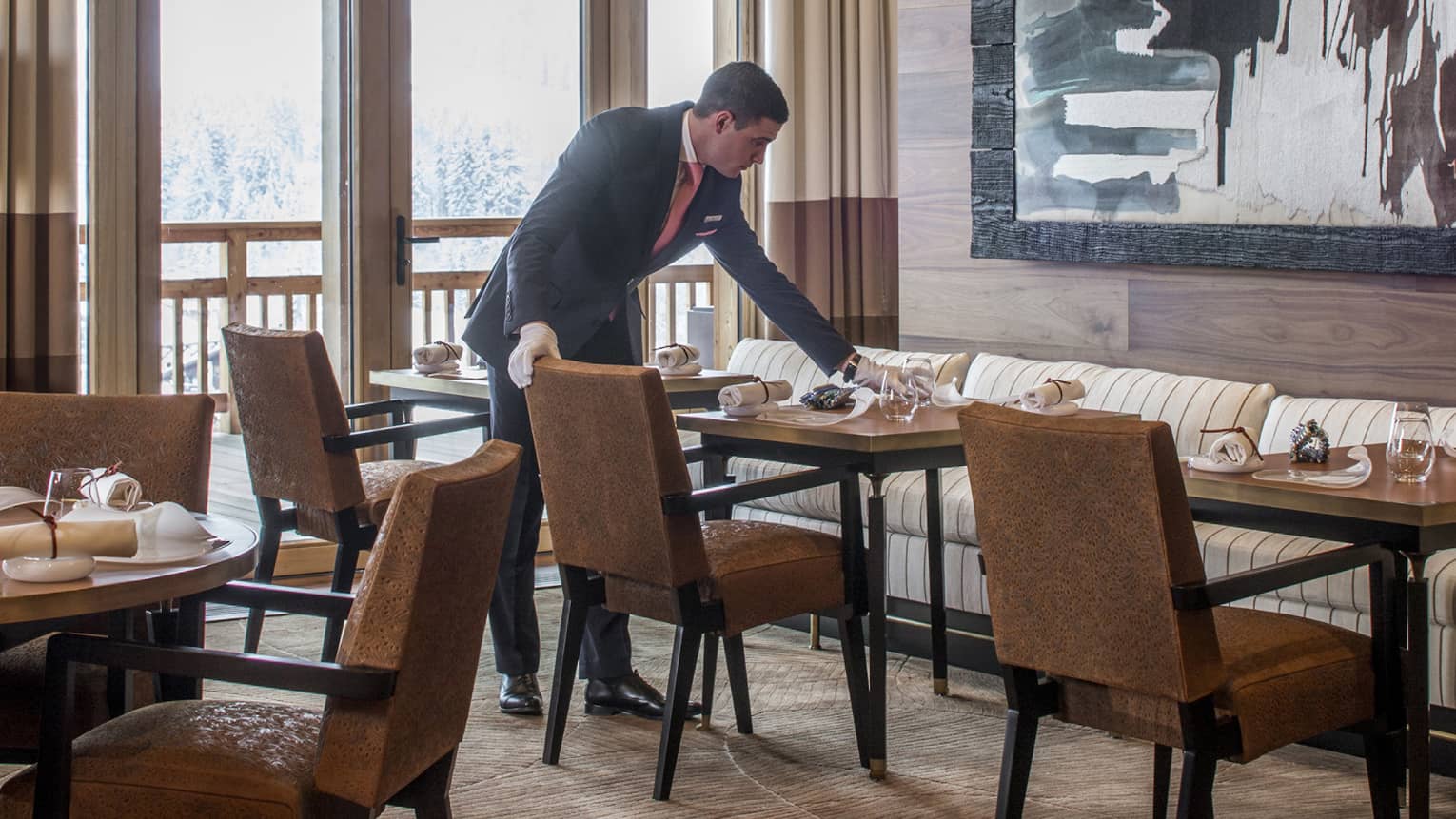 Server sets dining table under large, framed abstract painting in Le 1920 restaurant