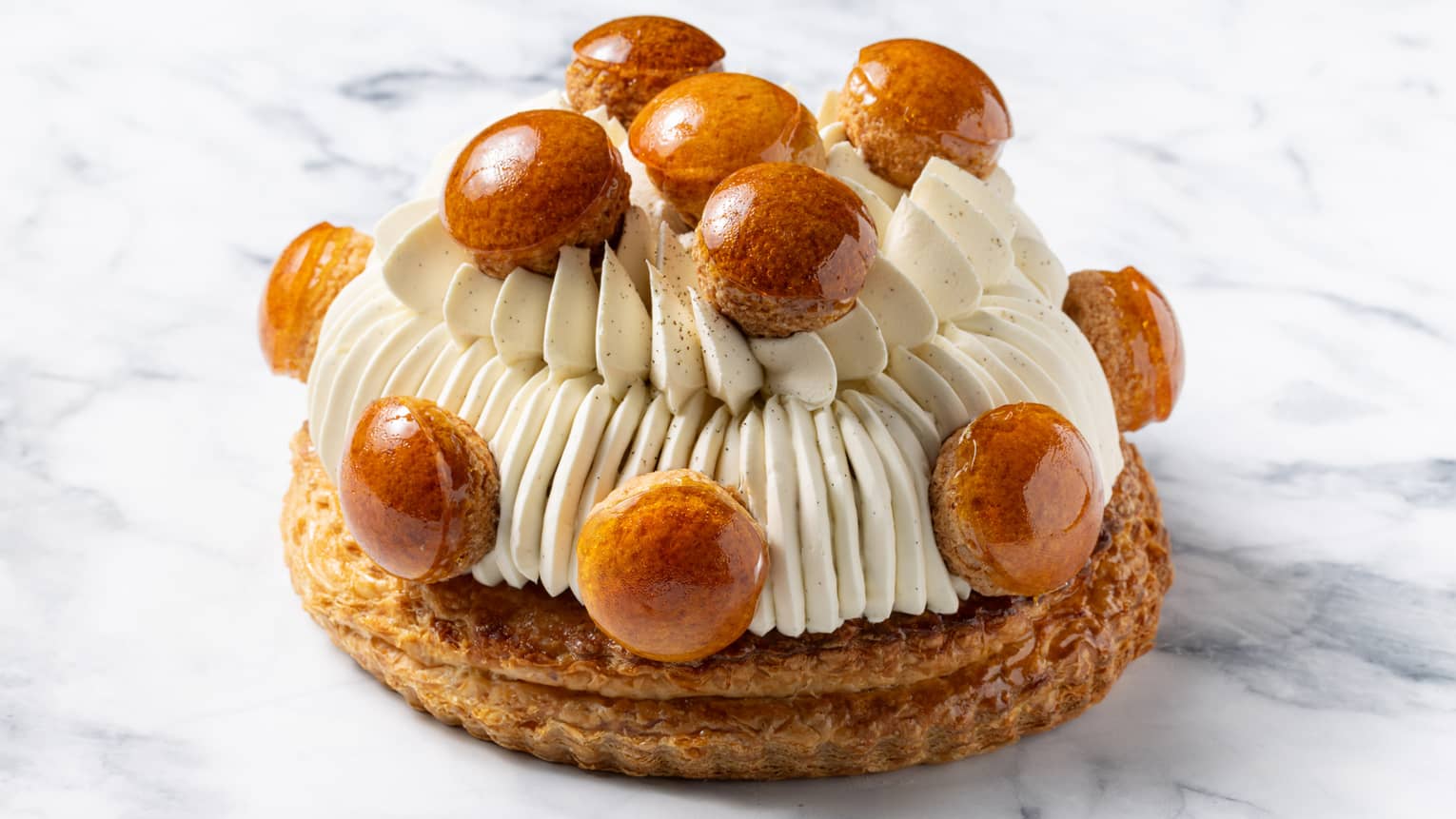 St. Honor� cake piped with choux and dotted with choux puffs on marble surface