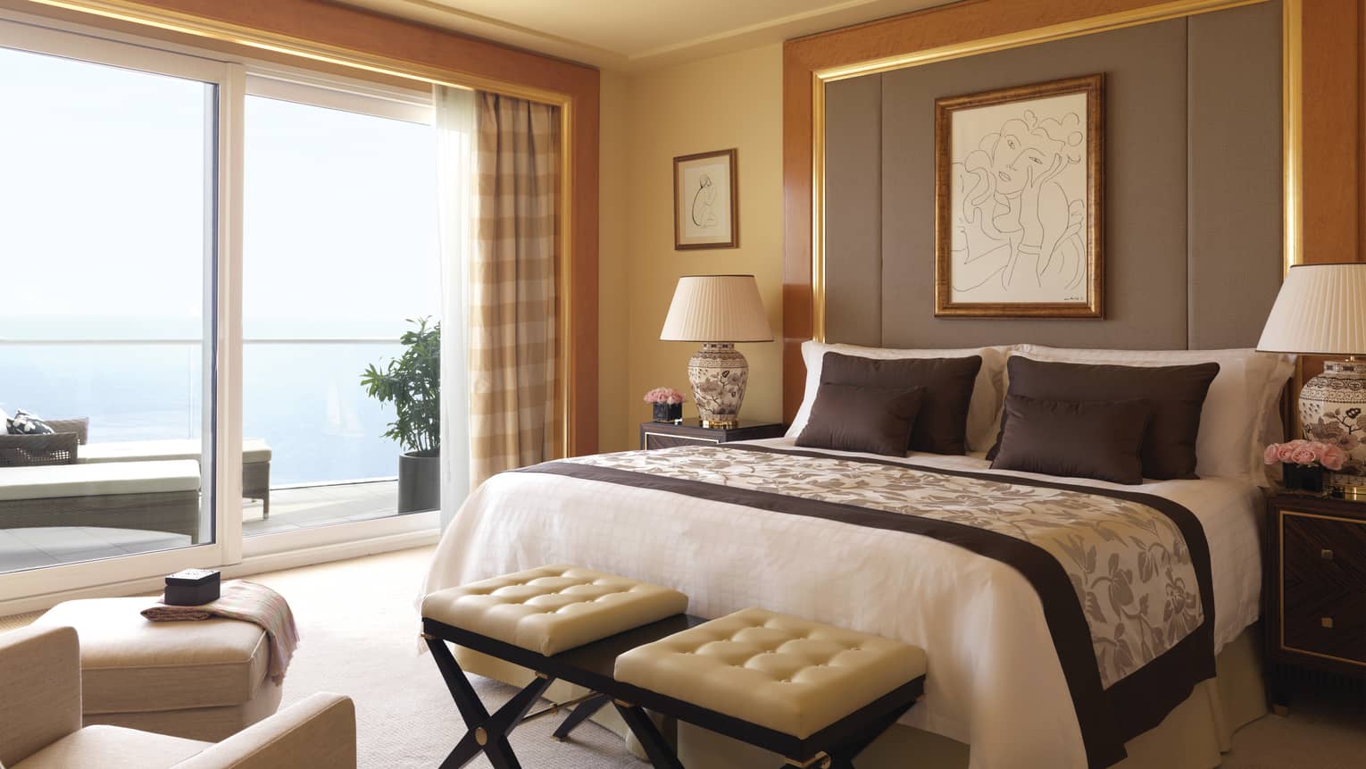 Diplomatic suite room with bed with tall upholstered headboard, bench with two white leather seats, white ottoman