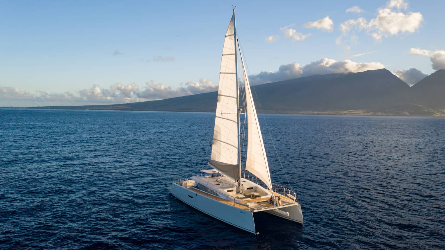 Catamaran sailing on the open water against mountain backdrop