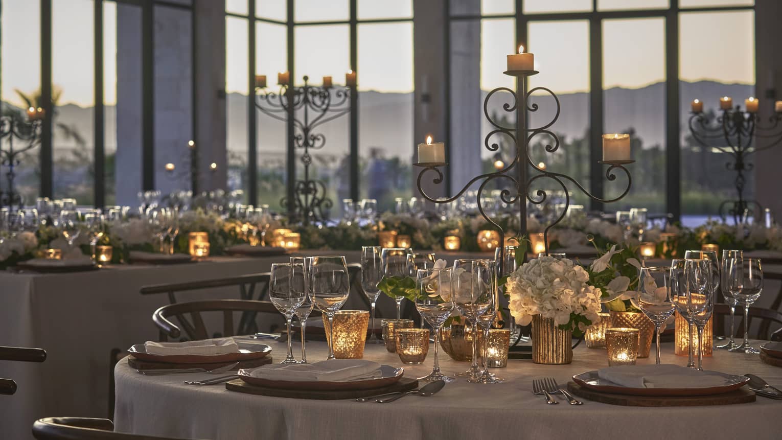 Floor to ceiling paneled windows let in the evening light into the glamorous ballroom, decorated with candles, white floral arrangements and crystal dinnerware.  