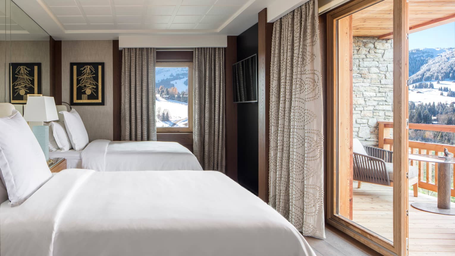 One-bedroom suite double beds by mirror wall facing glass balcony doors, patios
