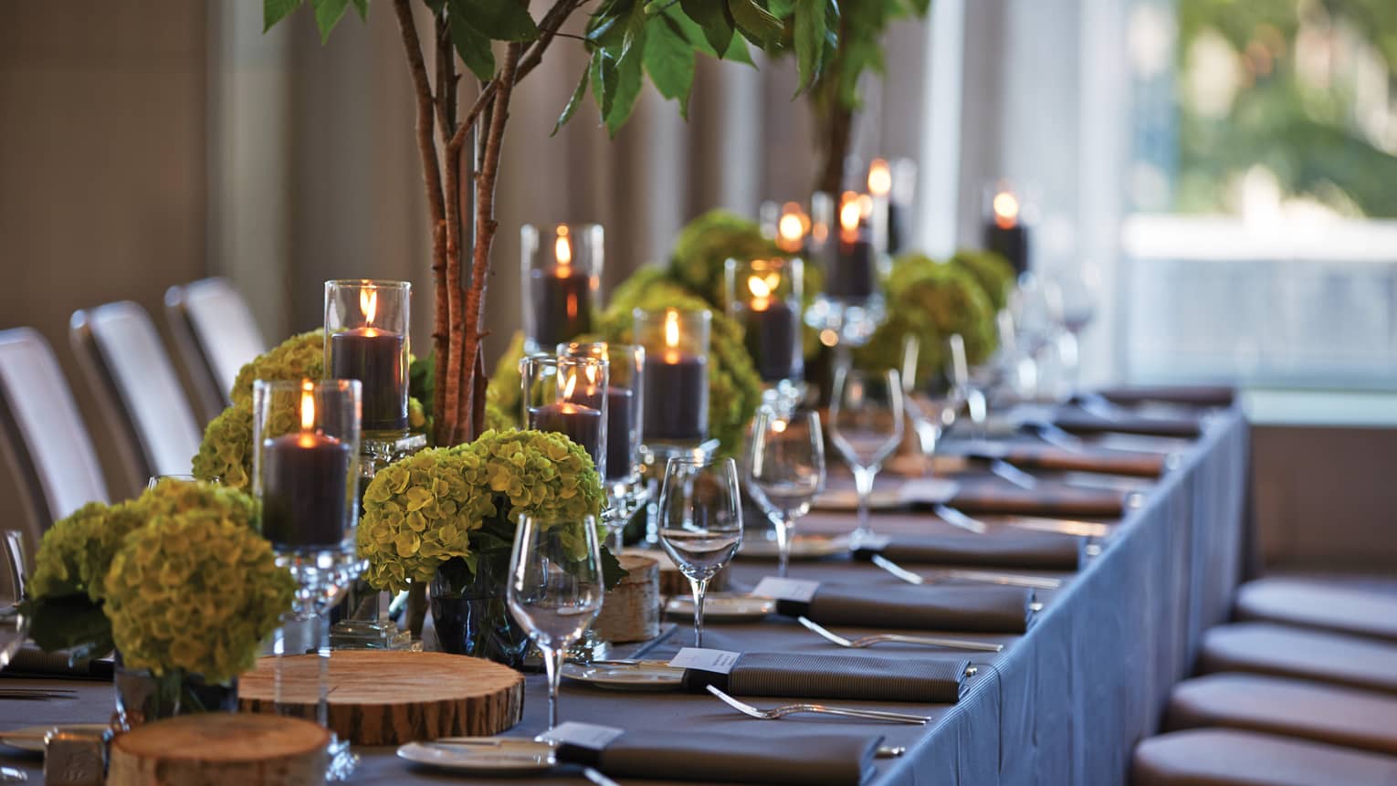 Black pillar candles in votives, green flowers, wine glasses along banquet table