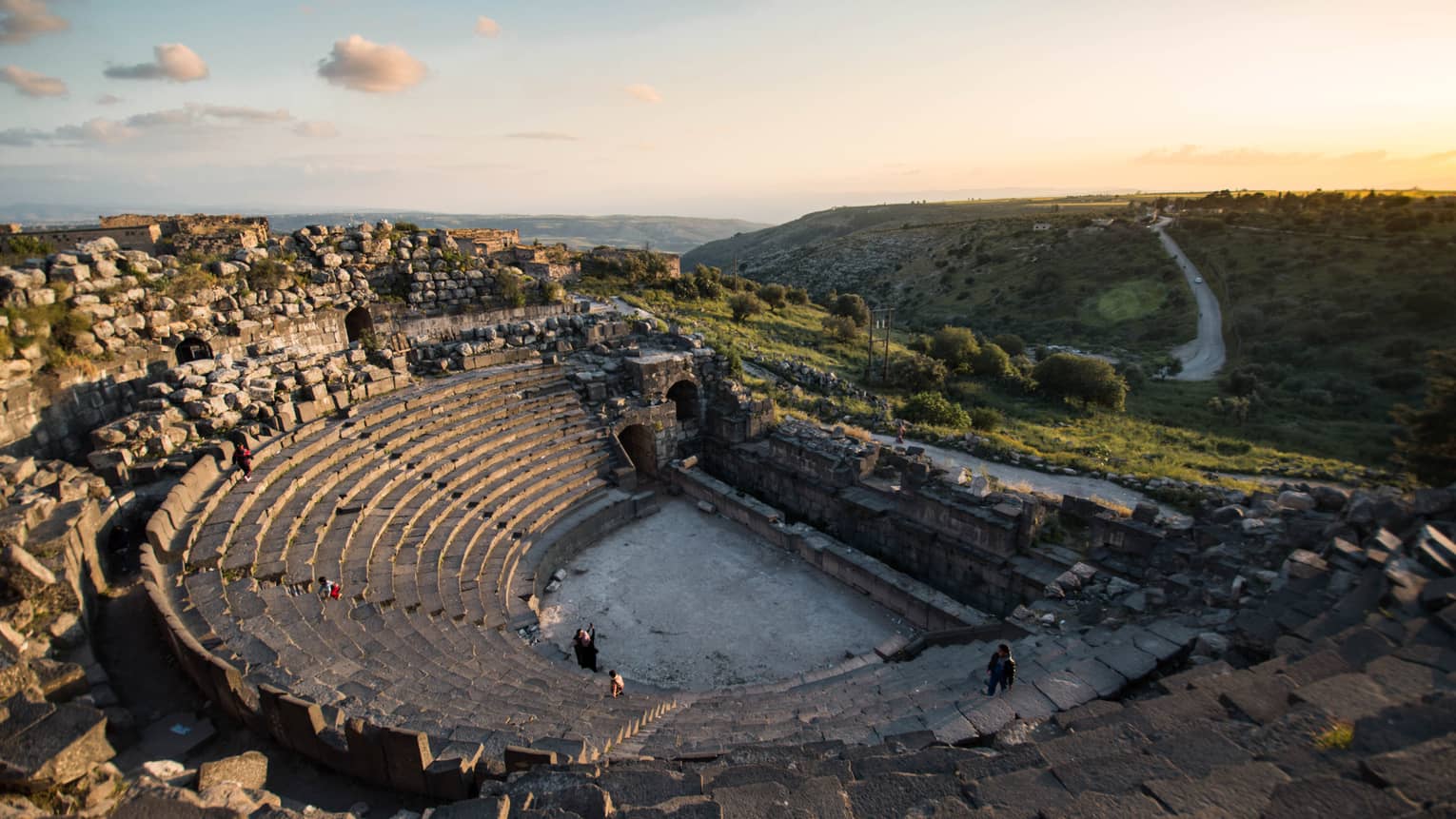 A coliseum with several rows of stone steps underneath a blue sky.