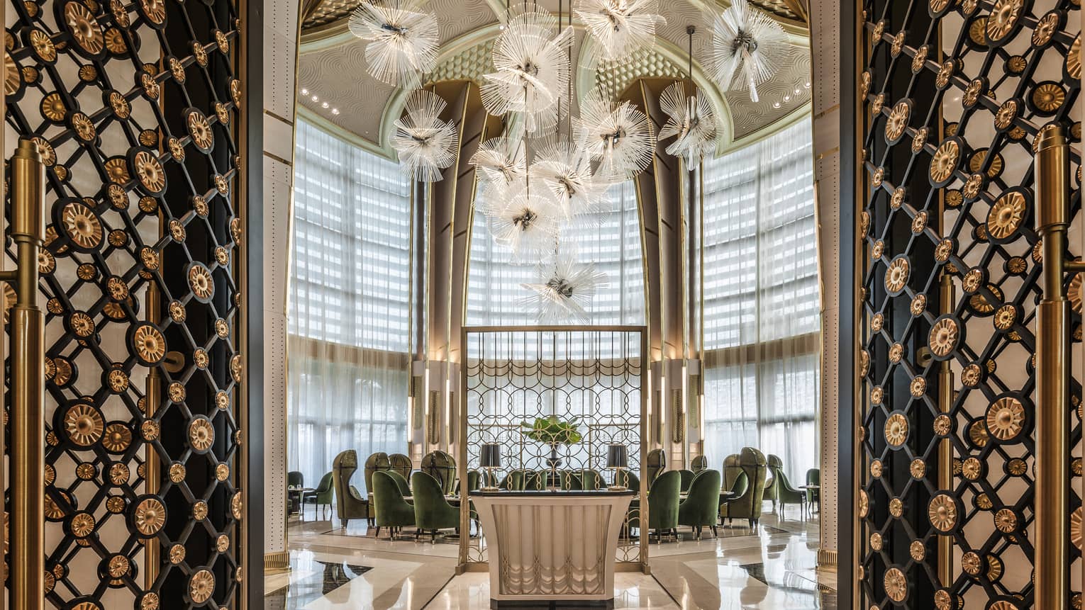 Decorative black-and-brass floral doors open to bright room with green velvet chairs under dome ceiling, modern art 