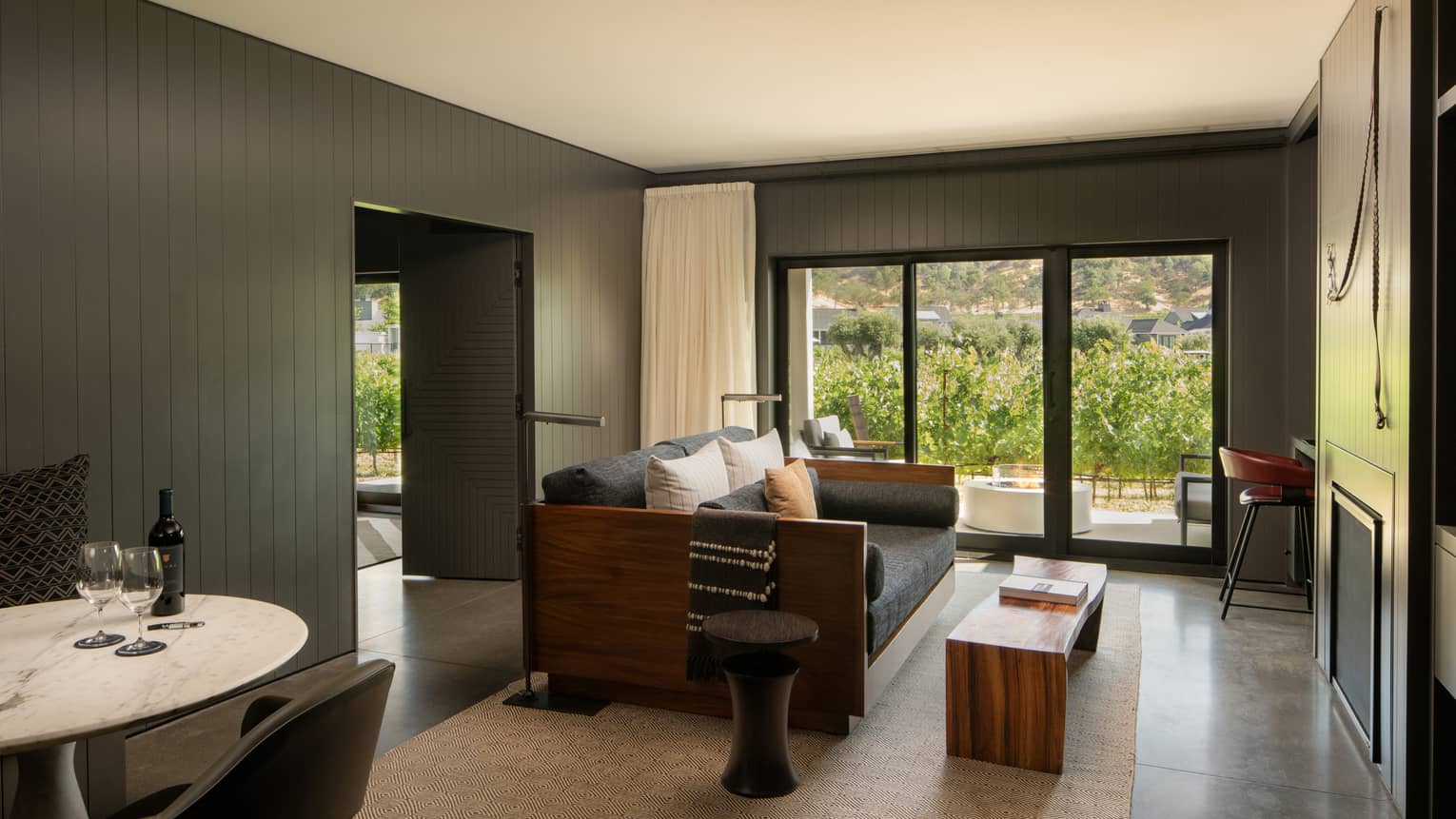 Modern living room of a resort suite, with dark grey-coloured walls and sofa, and a walk-out terrace