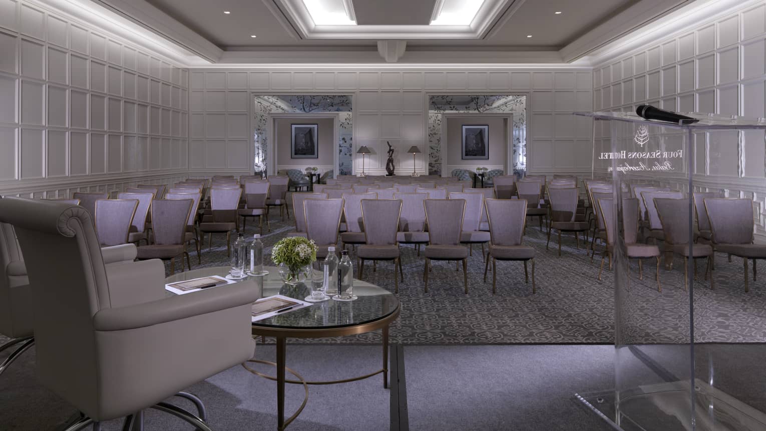 Glass podium, armchair facing rows of purple chairs in ballroom