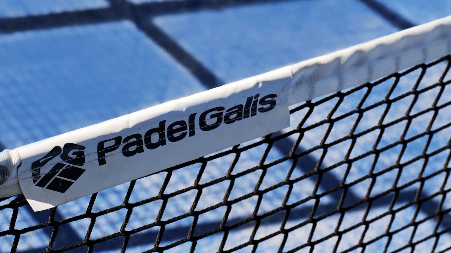 A close-up of the words, Padel Galis, and the company logo on a label of a net on a tennis court.