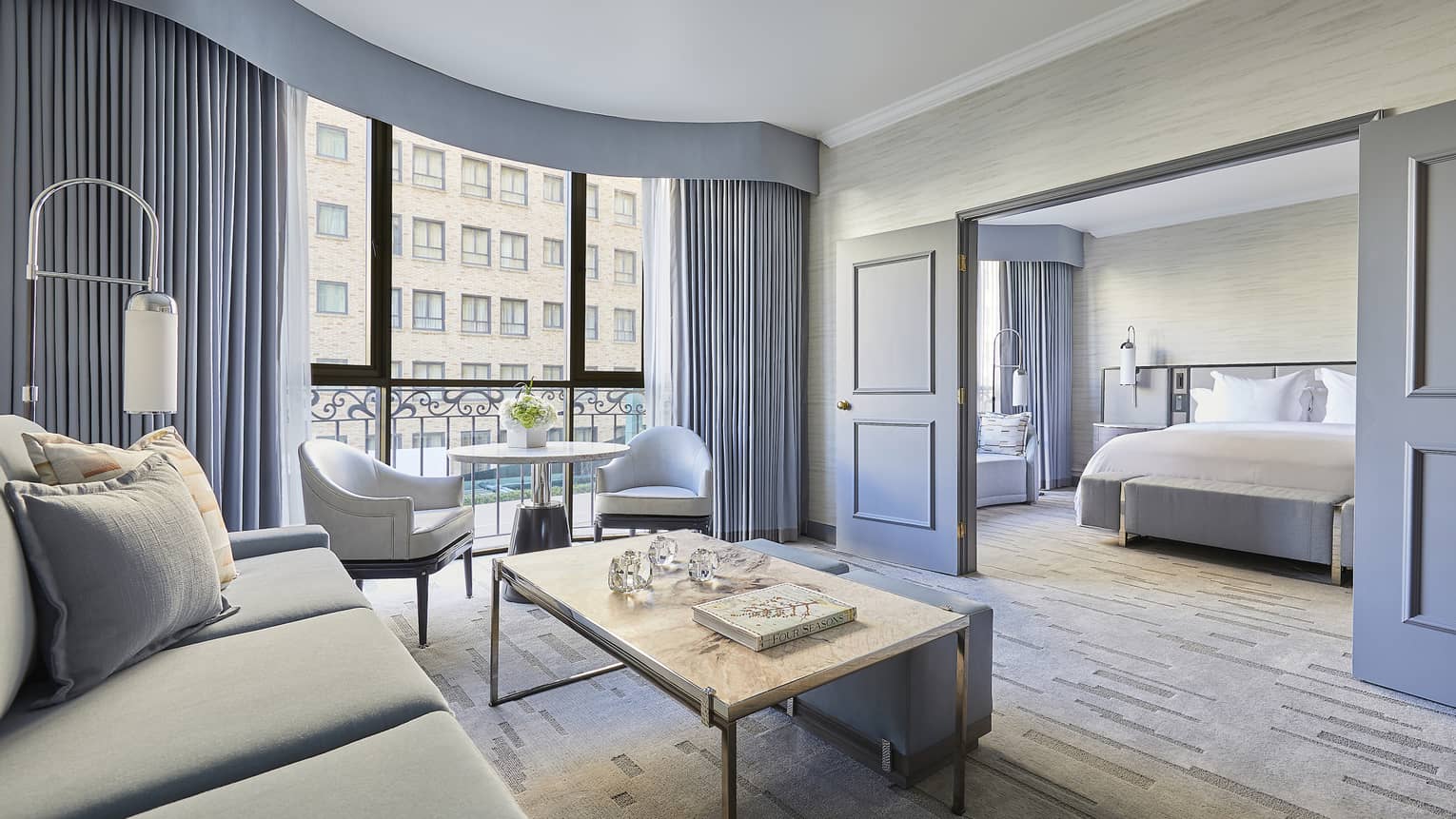 Hotel suite living room with view of a building, sliding doors into bedroom