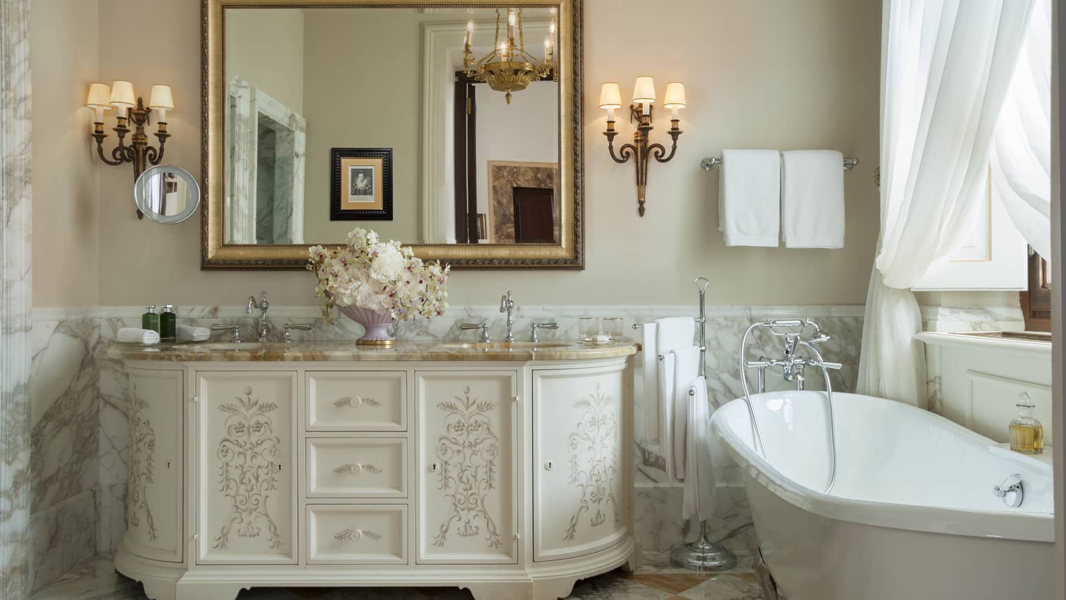 Gallery Suite bathroom at Four Seasons Hotel Florence, with marble floors, standalone tub, window and wooden vanity