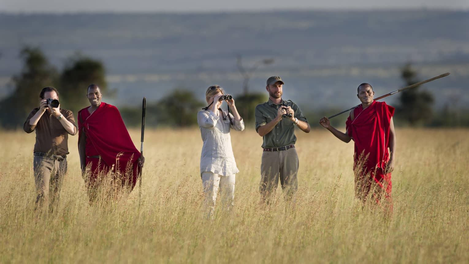 Couple takes photos on walking safari through tall grass with guides