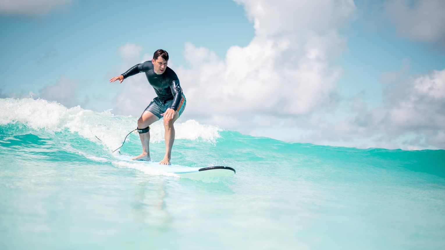 Man balances on surf board over wave