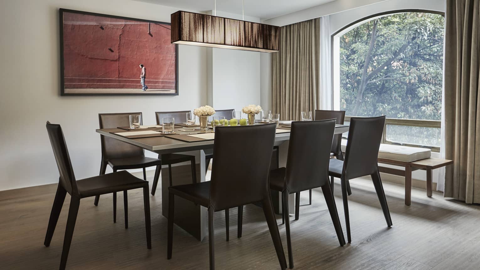 Private meeting table under modern light by sunny arched window, framed art on wall