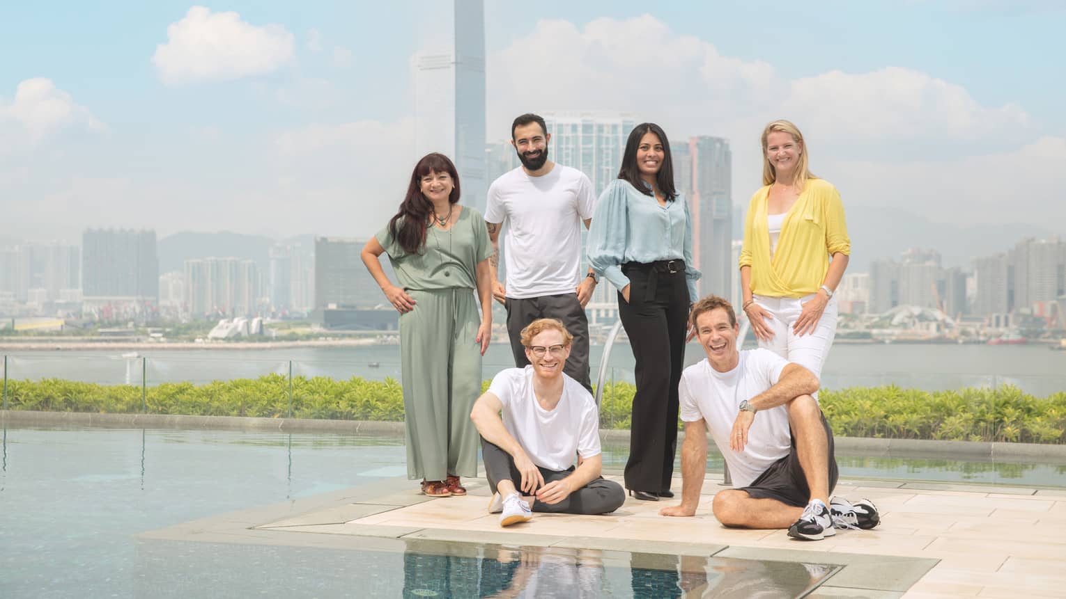 Resident healers pose at the outdoor pool, downtown Hong Kong in the background