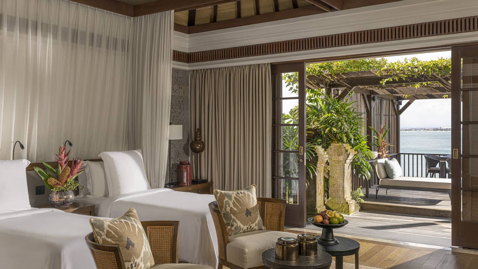Royal Villa bedroom with double canopy beds, armchairs, doorway to pool and lounge area