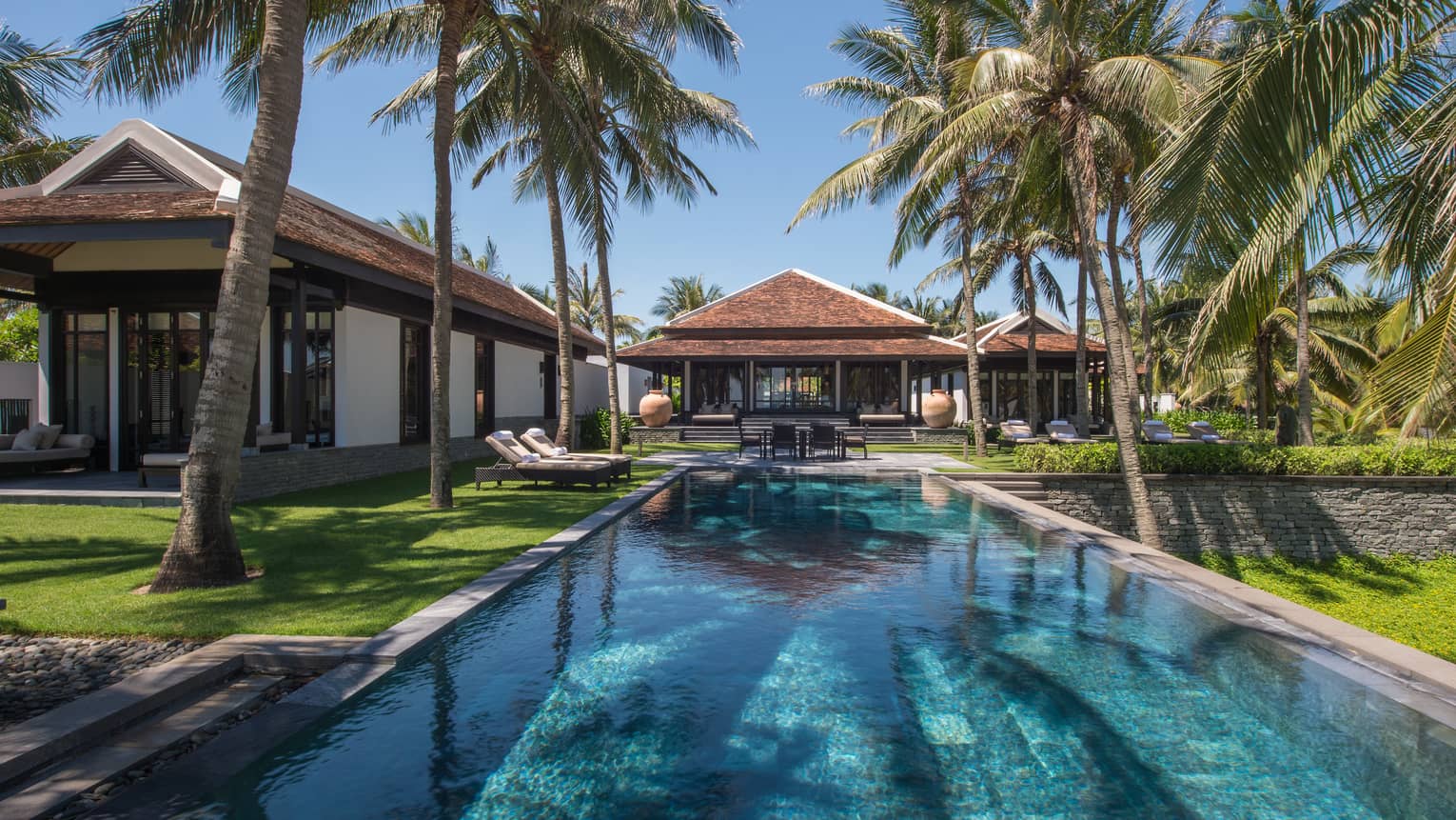 Two-Bedroom Pool Villa exterior at end of long outdoor swimming pool, lawns