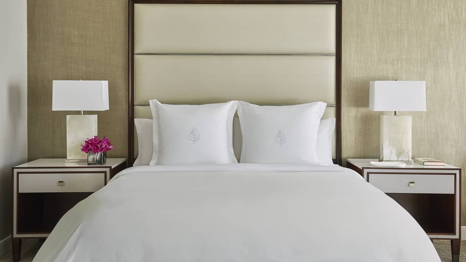 Deluxe Accessible Room head-on view of bed with white linens, tall padded beige headboard, nightstands with lamps