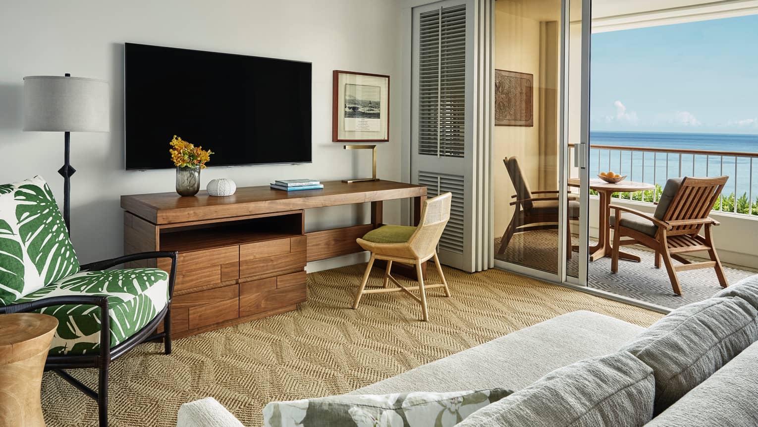 Oceanfront Suite large rustic wood desk under TV, palm print chair, open balcony doors