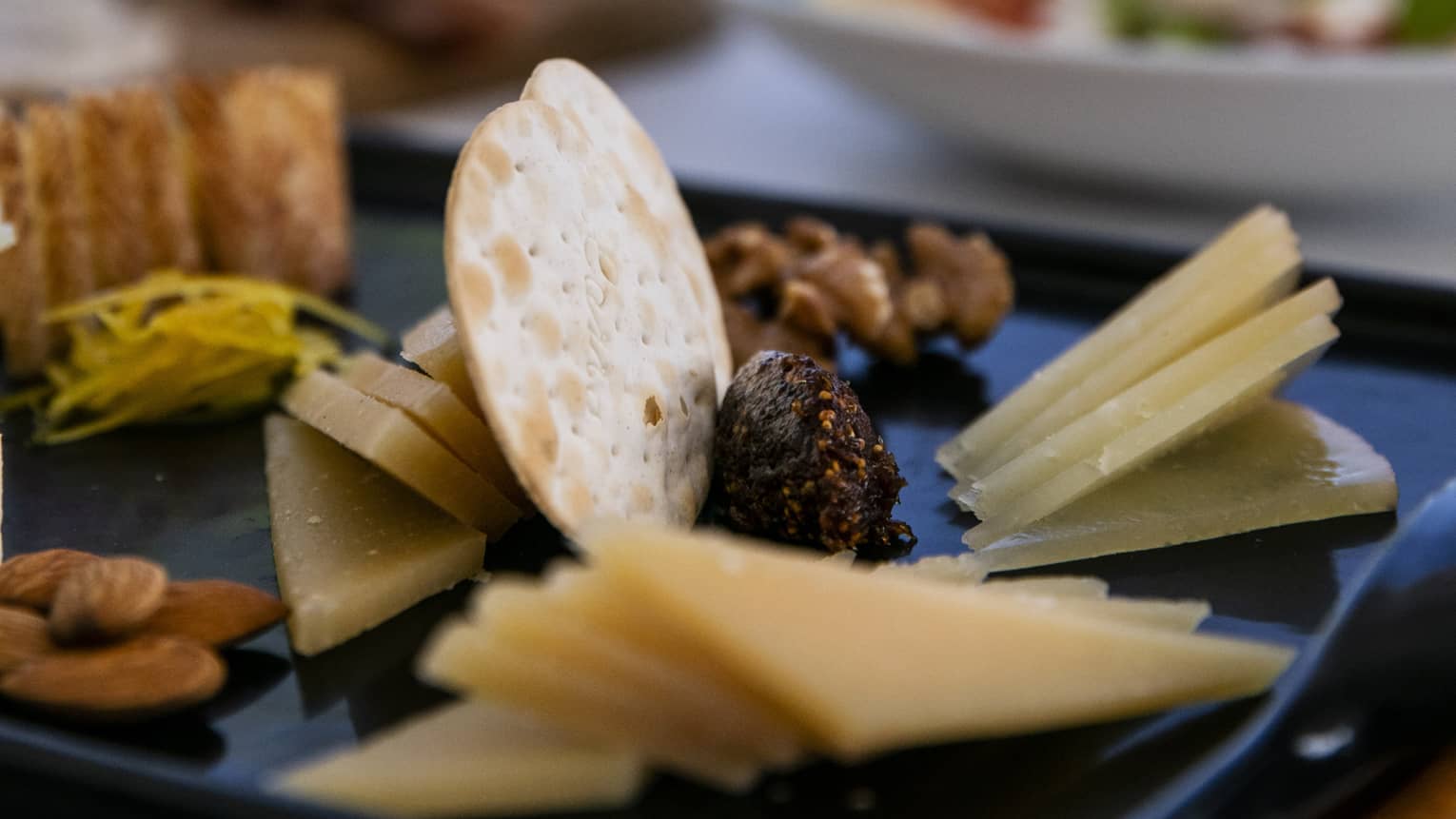 A charteurtie board with cheese, crackers, almonds and raisins
