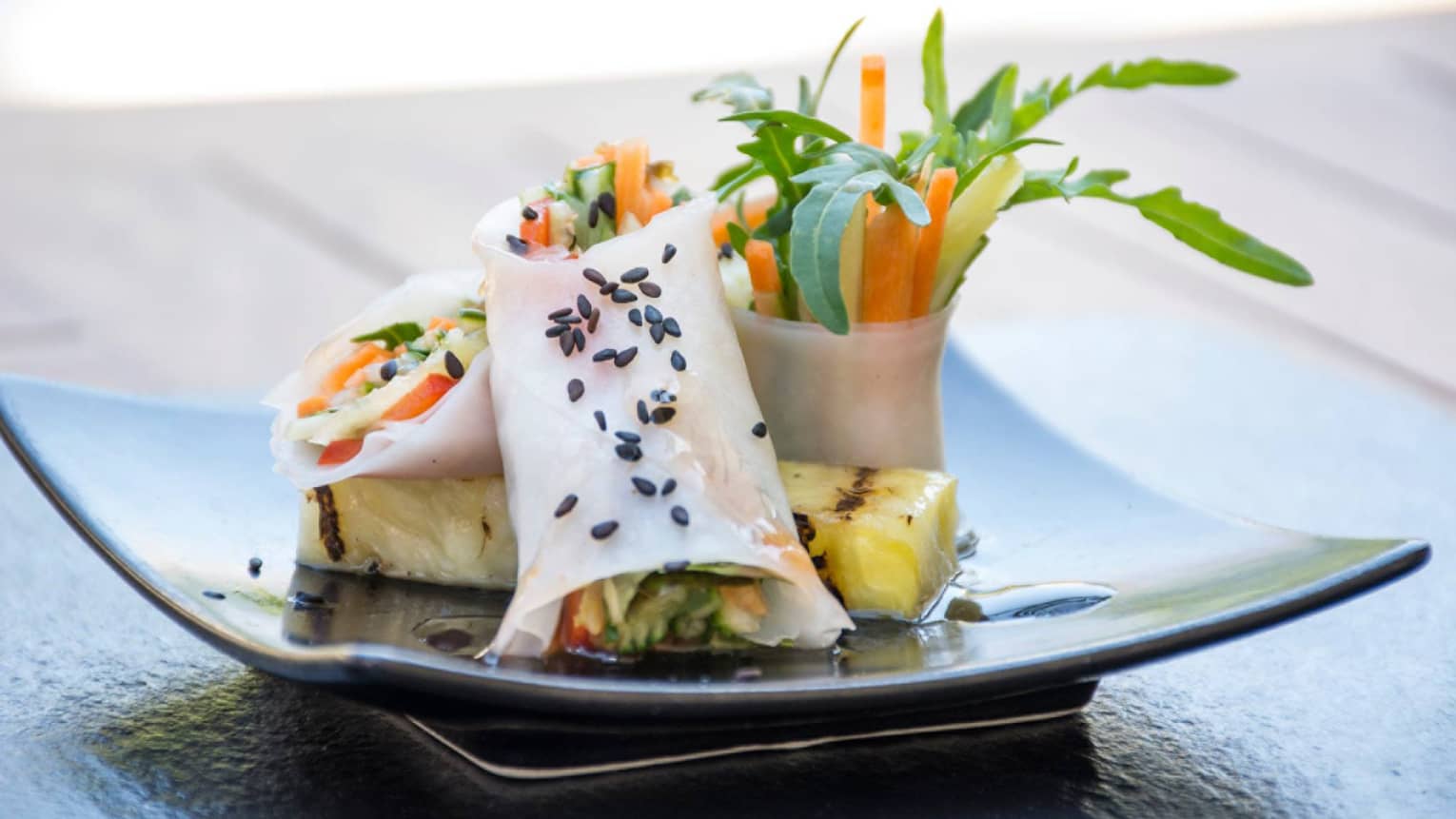 Spring rolls with carrot, mango and herbs in rice wraps, arranged on plate