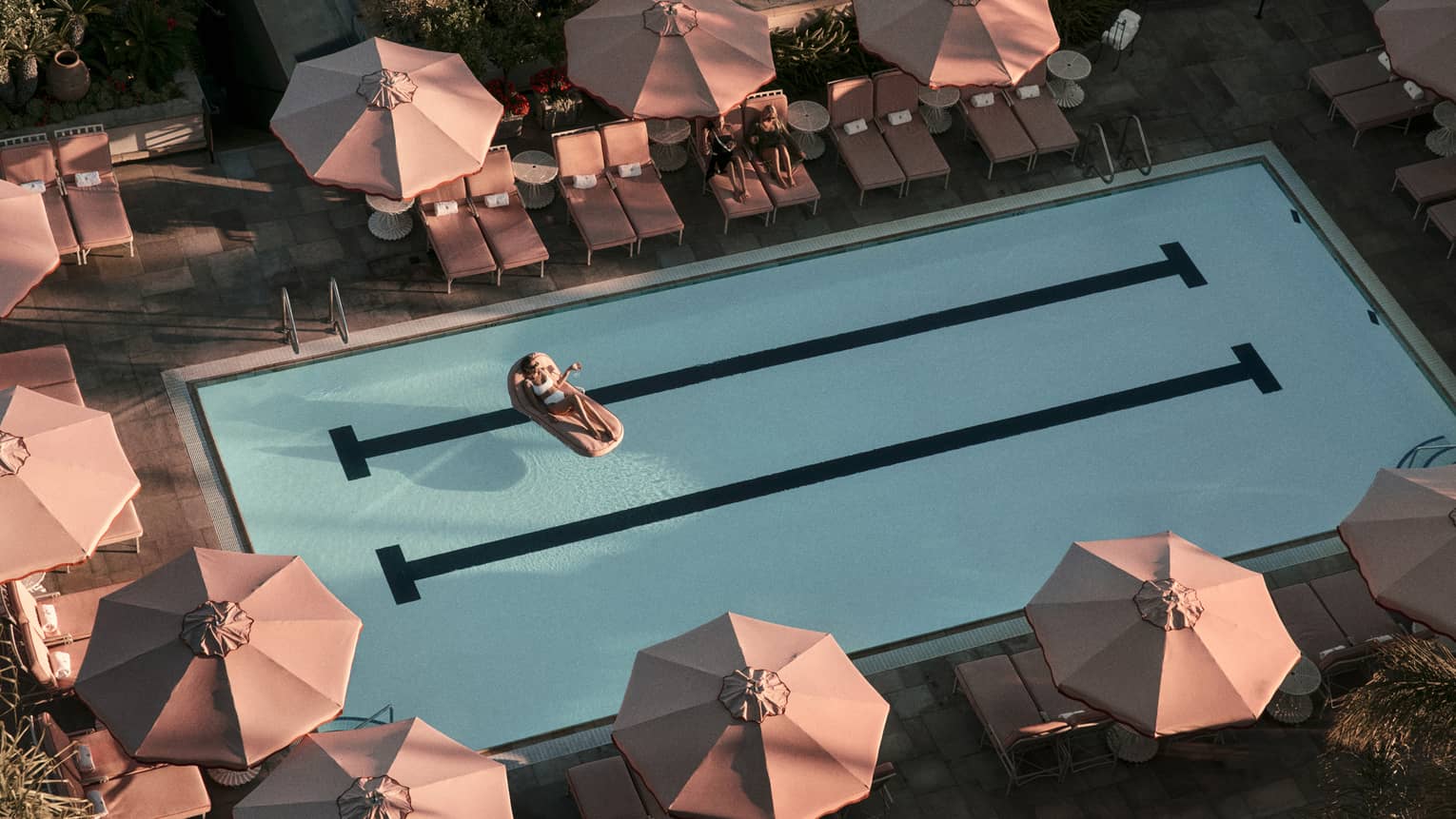 Hotel pool surrounded by pink umbrellas
