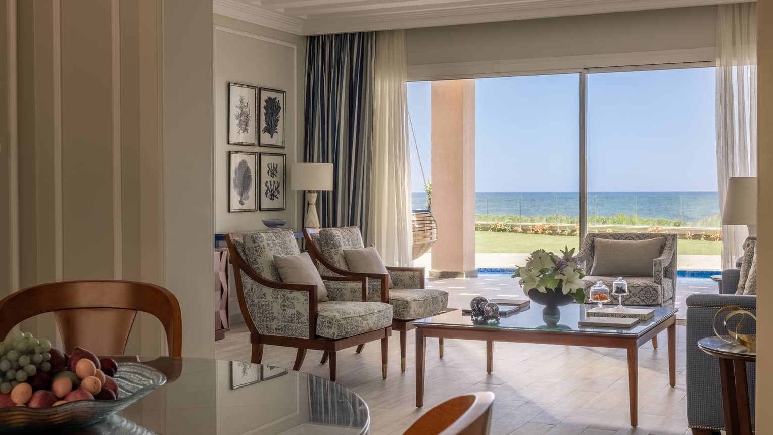 Two-Bedroom Beach Villa living area with three armchairs, blue sofa, glass coffee table, sliding glass door to terrace