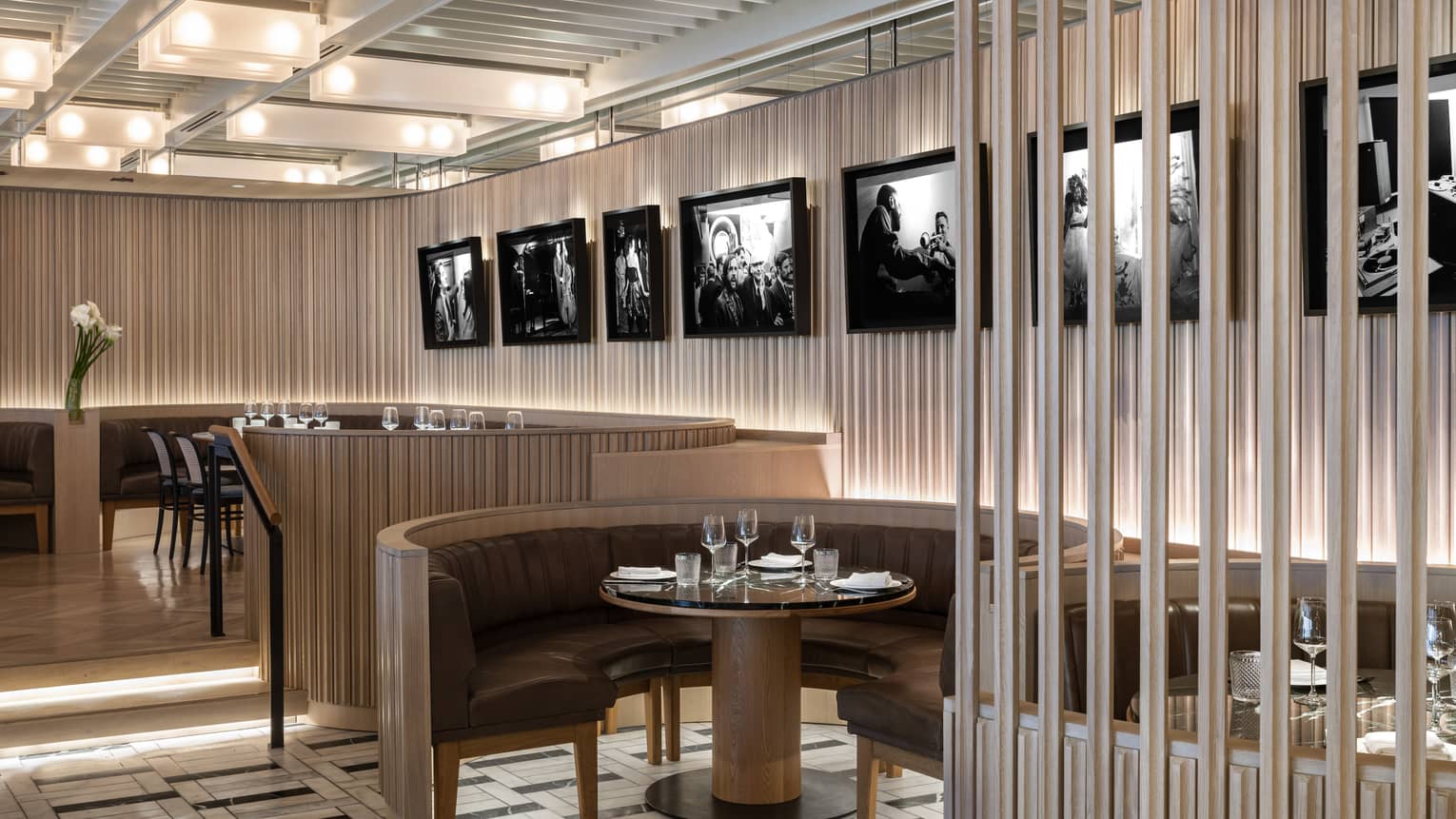 Thin, vertical panels of light-stained wood line the walls and the outside edges of the curved banquet-style tables at MARCUS Restaurant, with black-and-white photography hanging on the walls