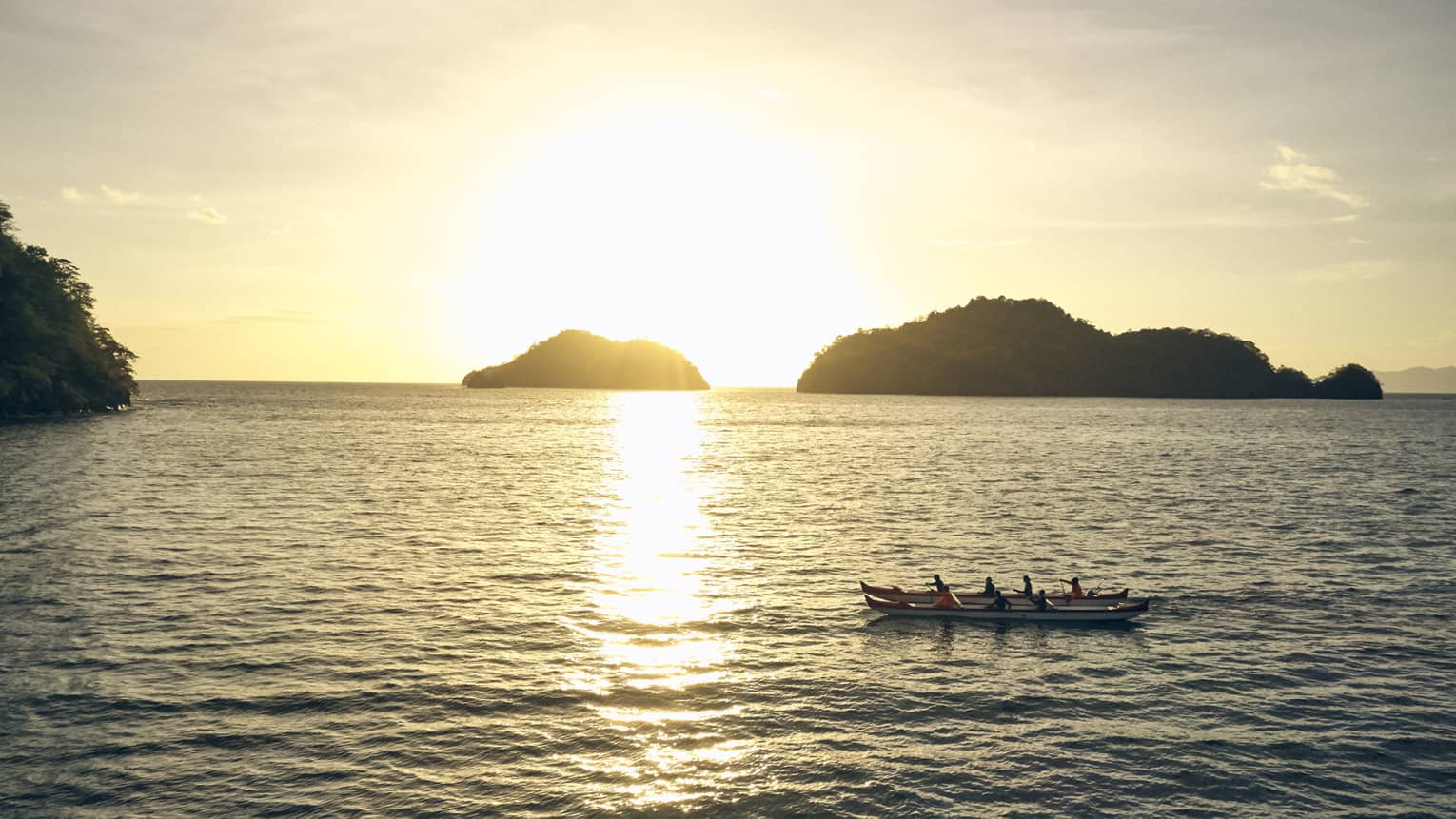 People in a canoe during sunrise.