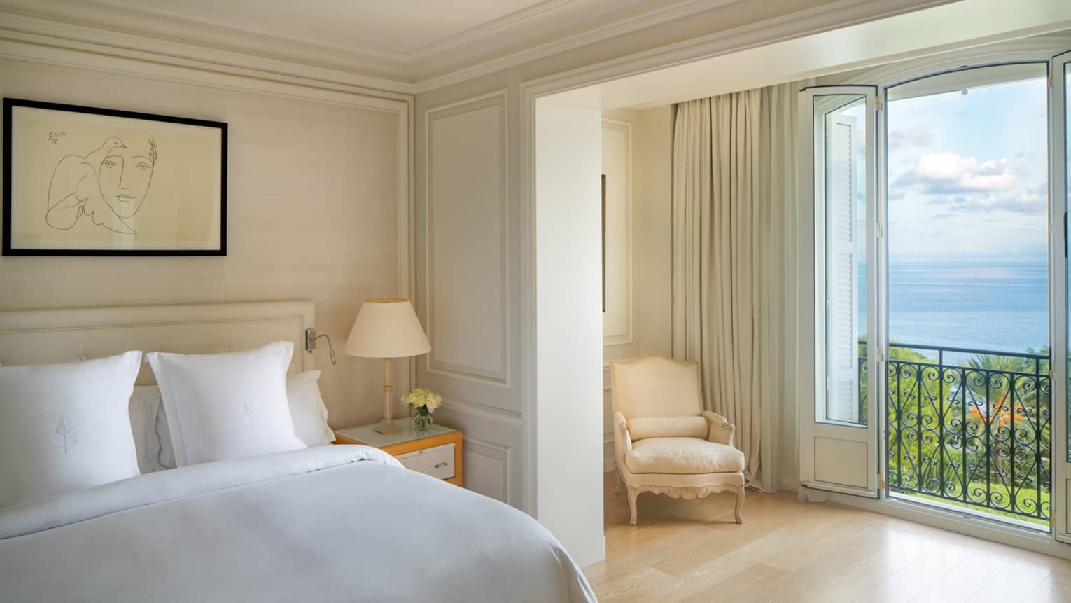 Palace Seaview Suite with white bed, framed line art above, white lamp and chaise, sea views