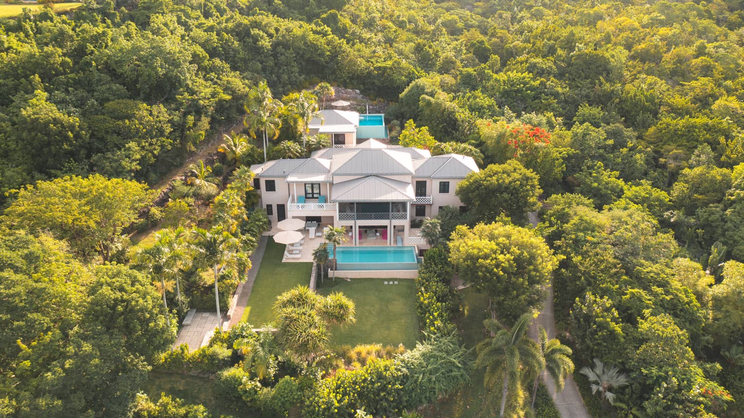 Aerial view of private villa with pool, surrounded by tropical green trees