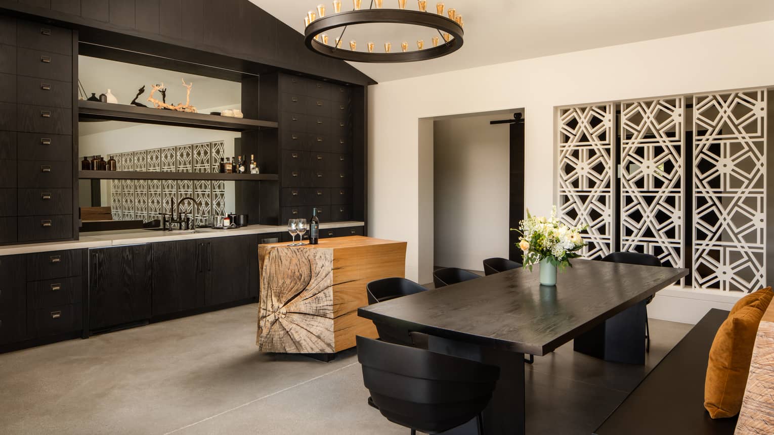 Sleek, dark-wood dining table for eight, next to a modern kitchen featuring natural wood block island