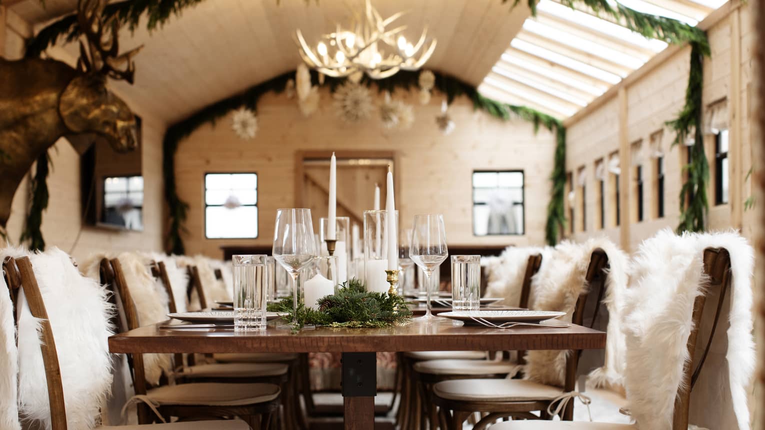 A table decorated with garland and fur chair covers in a cabin-themed dining room