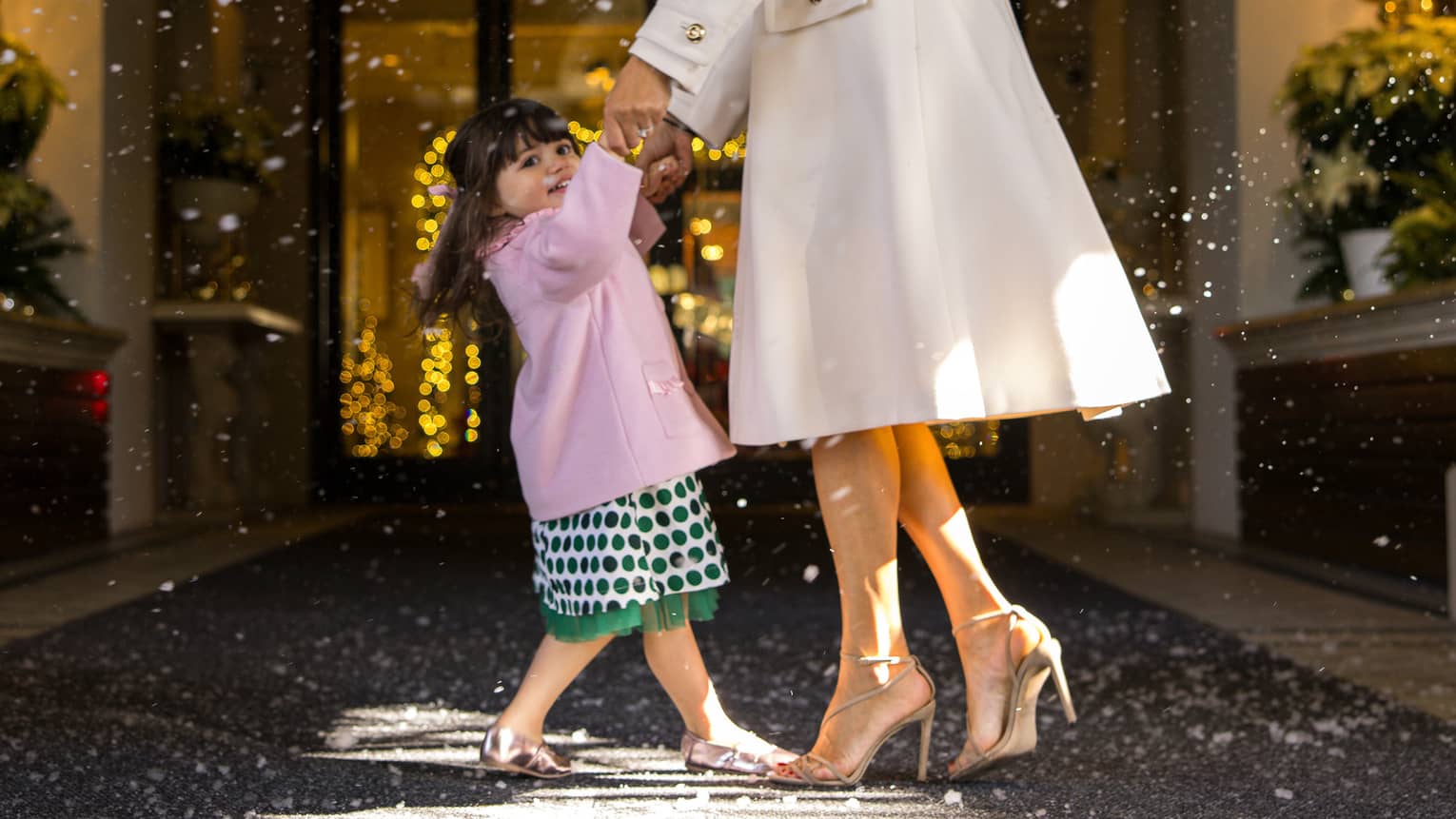 Mother and child dancing duner faux snow falling over a hotel entrance