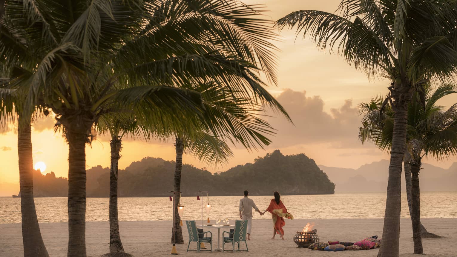 A man and woman on a beach having a Punta chintai private dinner at Four Seasons Langkawi
