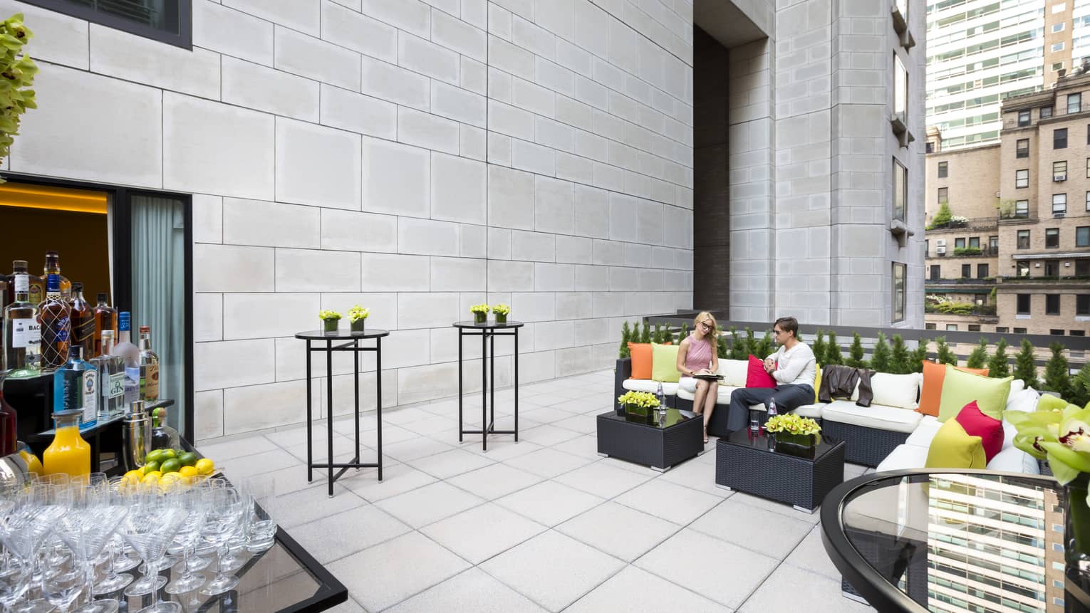 Couple on wicker sofa at cocktail reception on sunny eleventh floor patio lounge