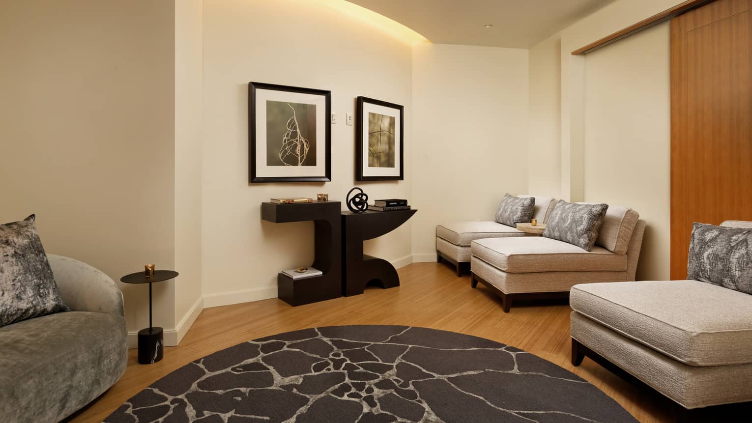 A room with comfortable three large chairs for relaxing, there is a round grey rug and painting on the wall.