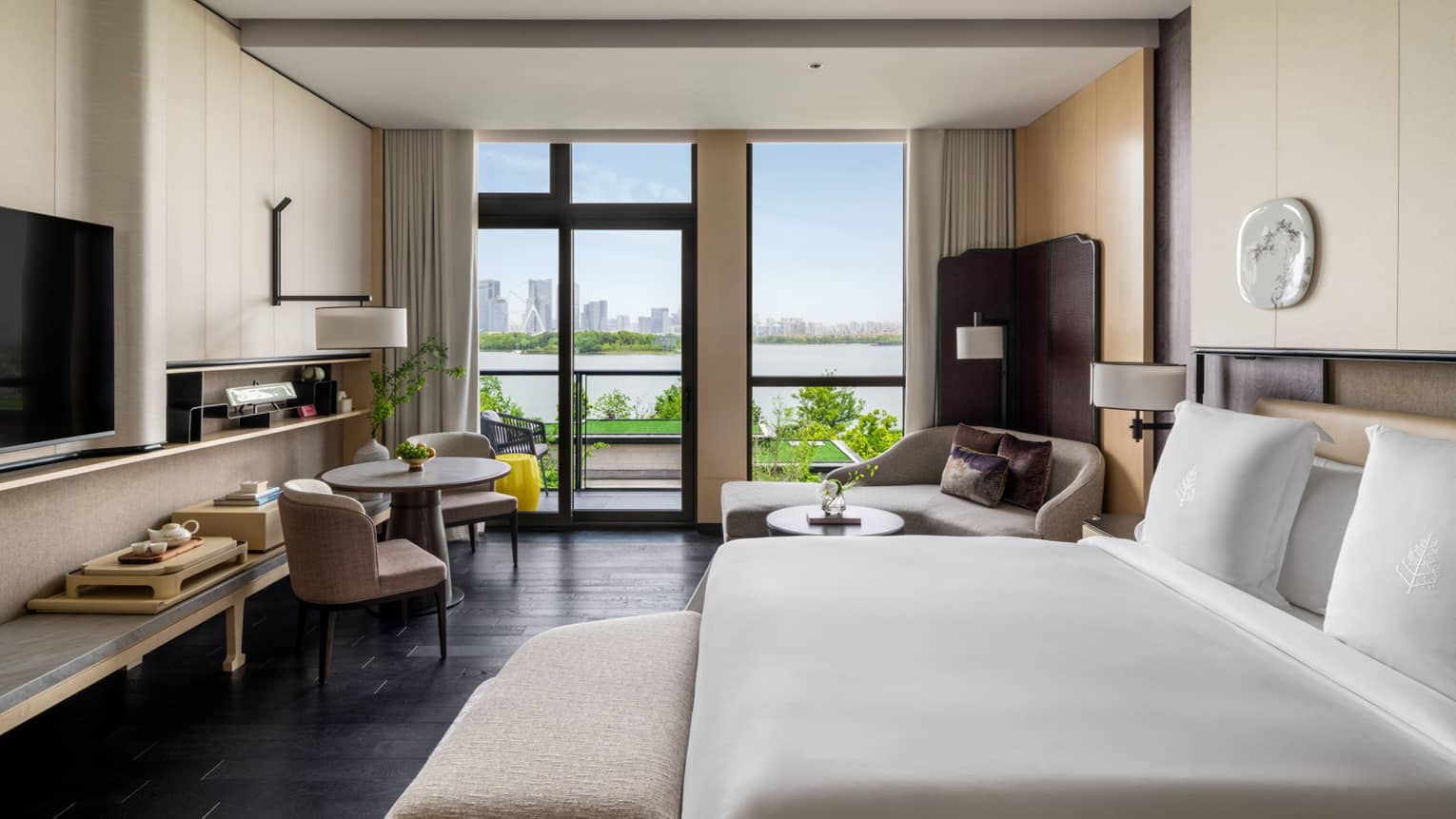 Luxury hotel room with king bed, chaise, small table and two chairs, and lake view at Four Seasons Hotel Suzhou