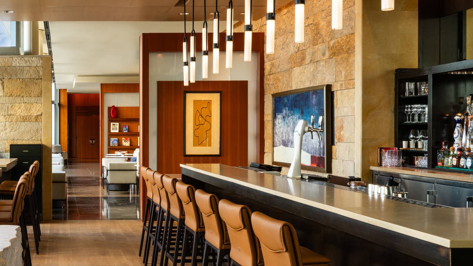 A bar with leather chairs and lighting overhead