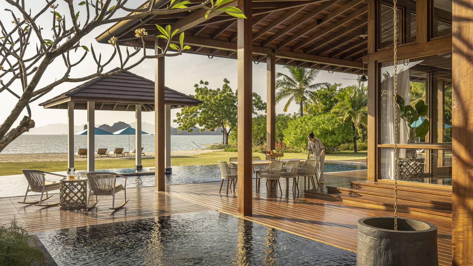 Private pool terrace and wooden deck under pergola, looking out to green lawn and Langkawi beach