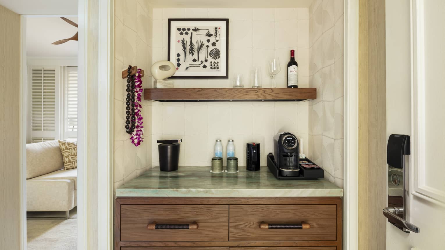 A wet bar within a contemporary resort room, featuring a coffee machine, water, ice bucket and a bottle of wine