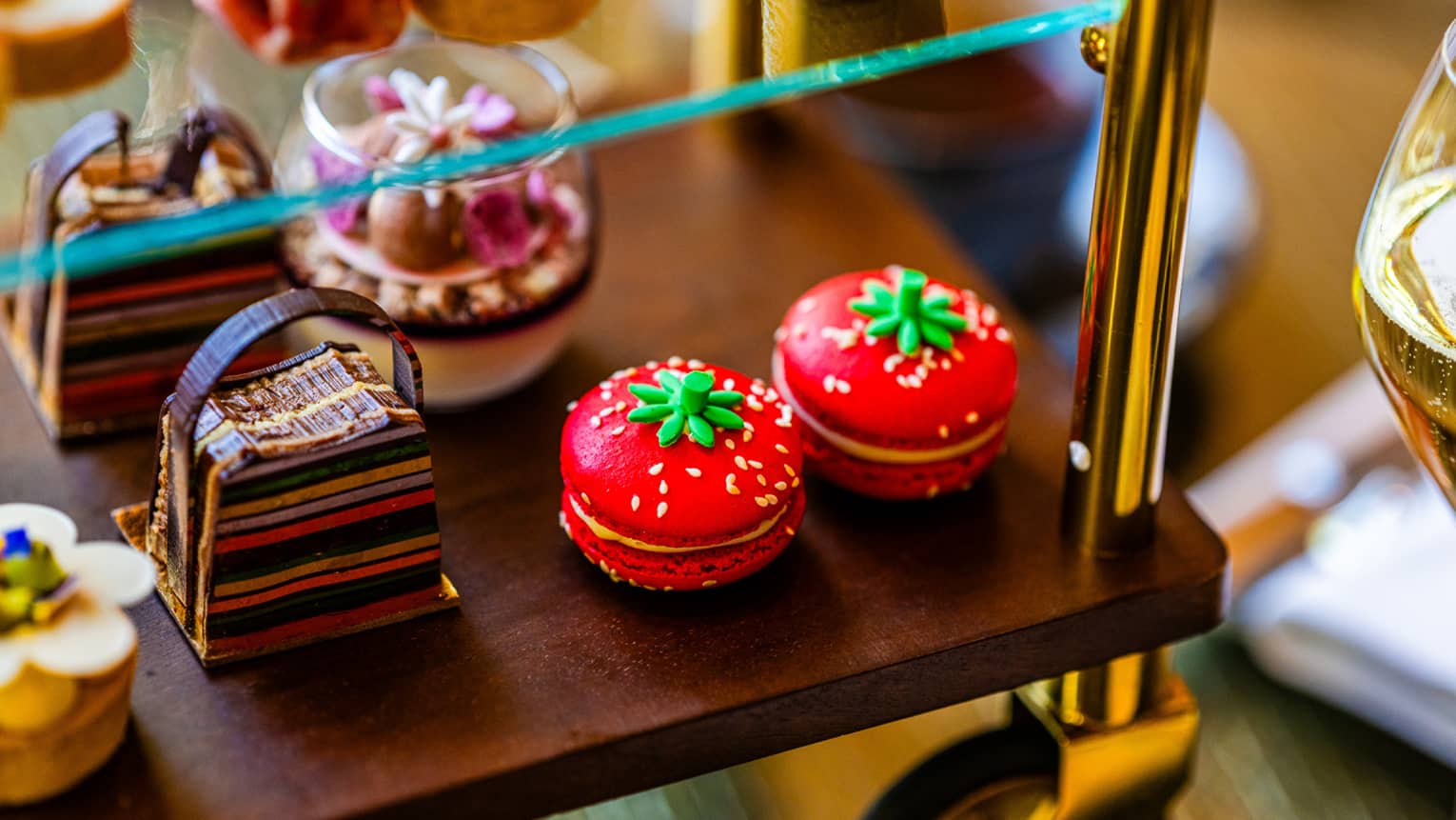 Two red macarons on a display with other sweets