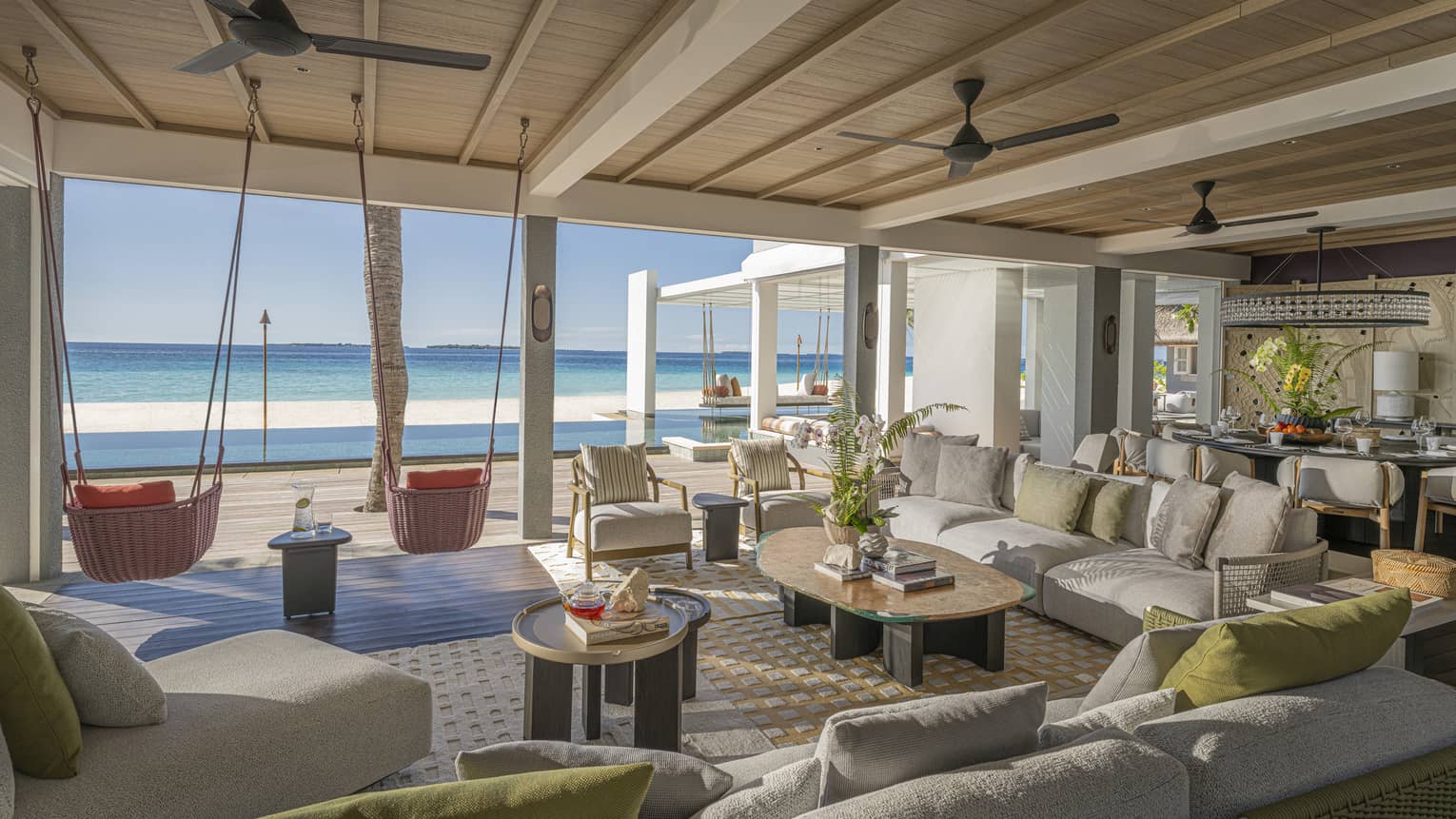 Large living room of private estate opening to a beachfront pool terrace with two hanging chairs