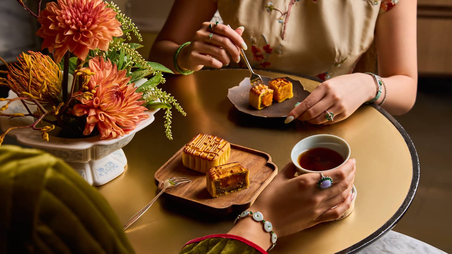 Two people dine at a restaurant table with plates of Chinese mooncakes