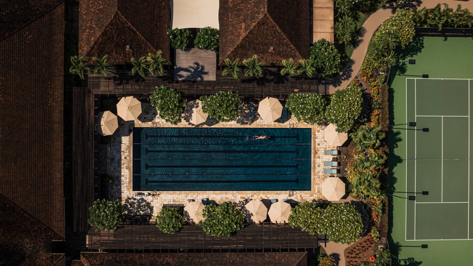 Aerial view of rectangular resort pool, near tennis court