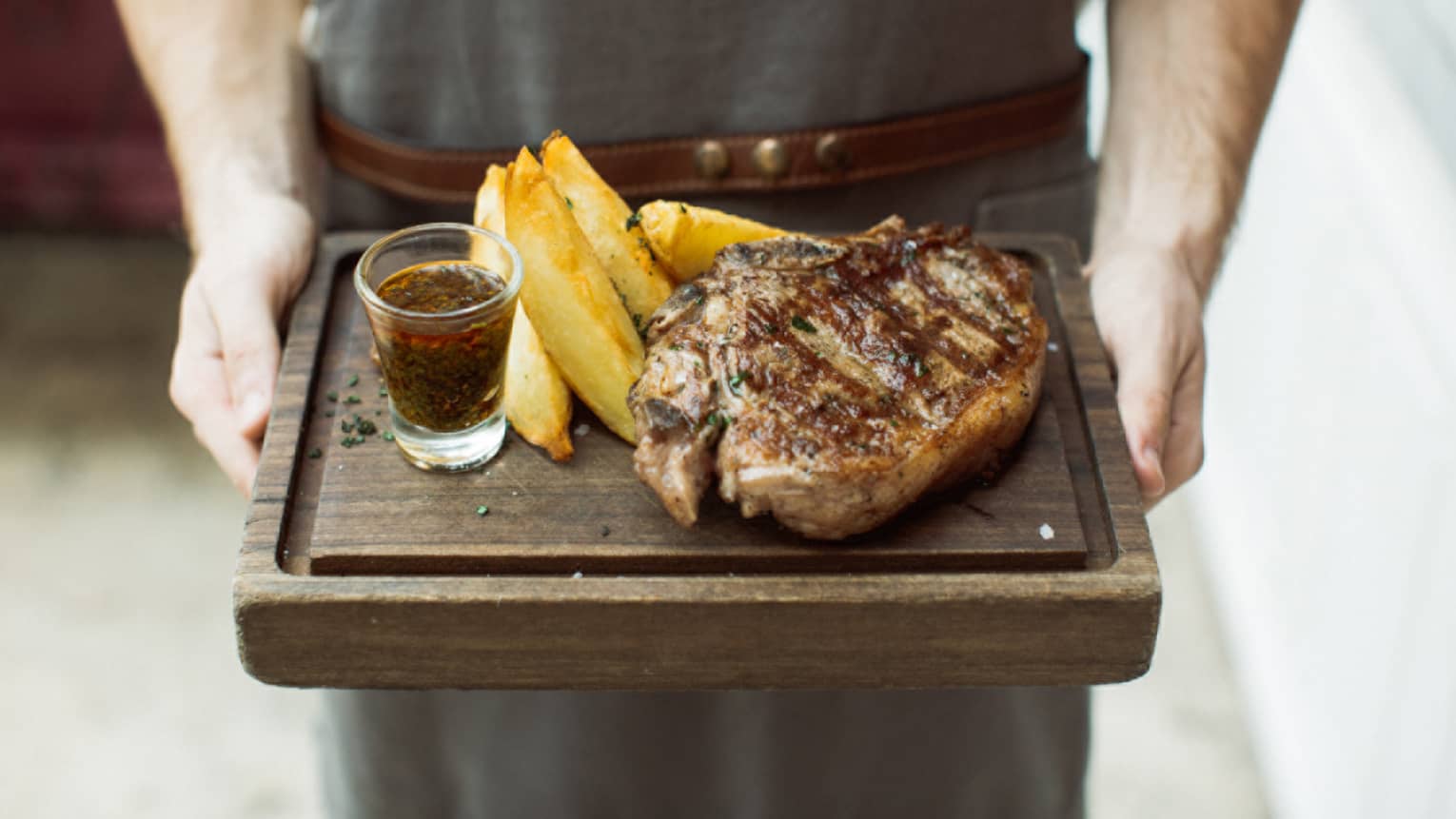 a 400-gram rib eye is served with chimichurri sauce and potato wedges