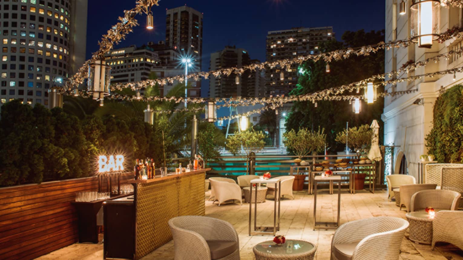 Strings of lights over rooftop patio seating area at night