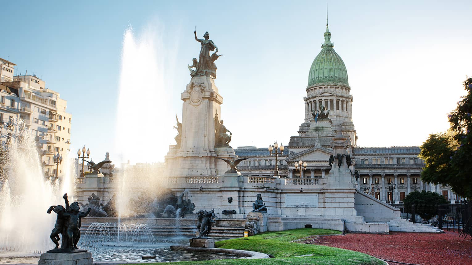 Large fountain, historic building and courtyard on sunny day